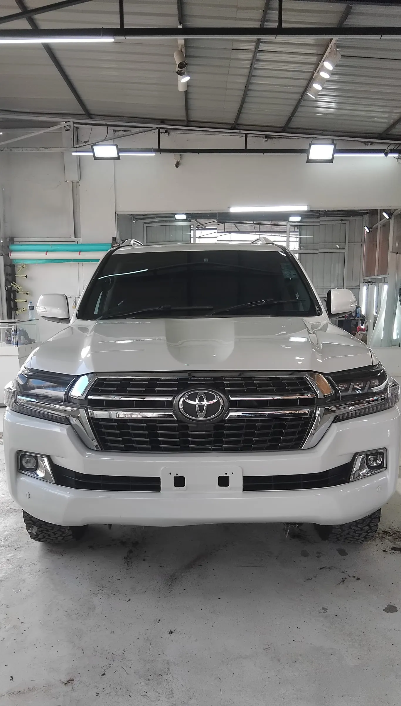 Head-on view of a white Toyota Land Cruiser inside the Melly Customs workshop