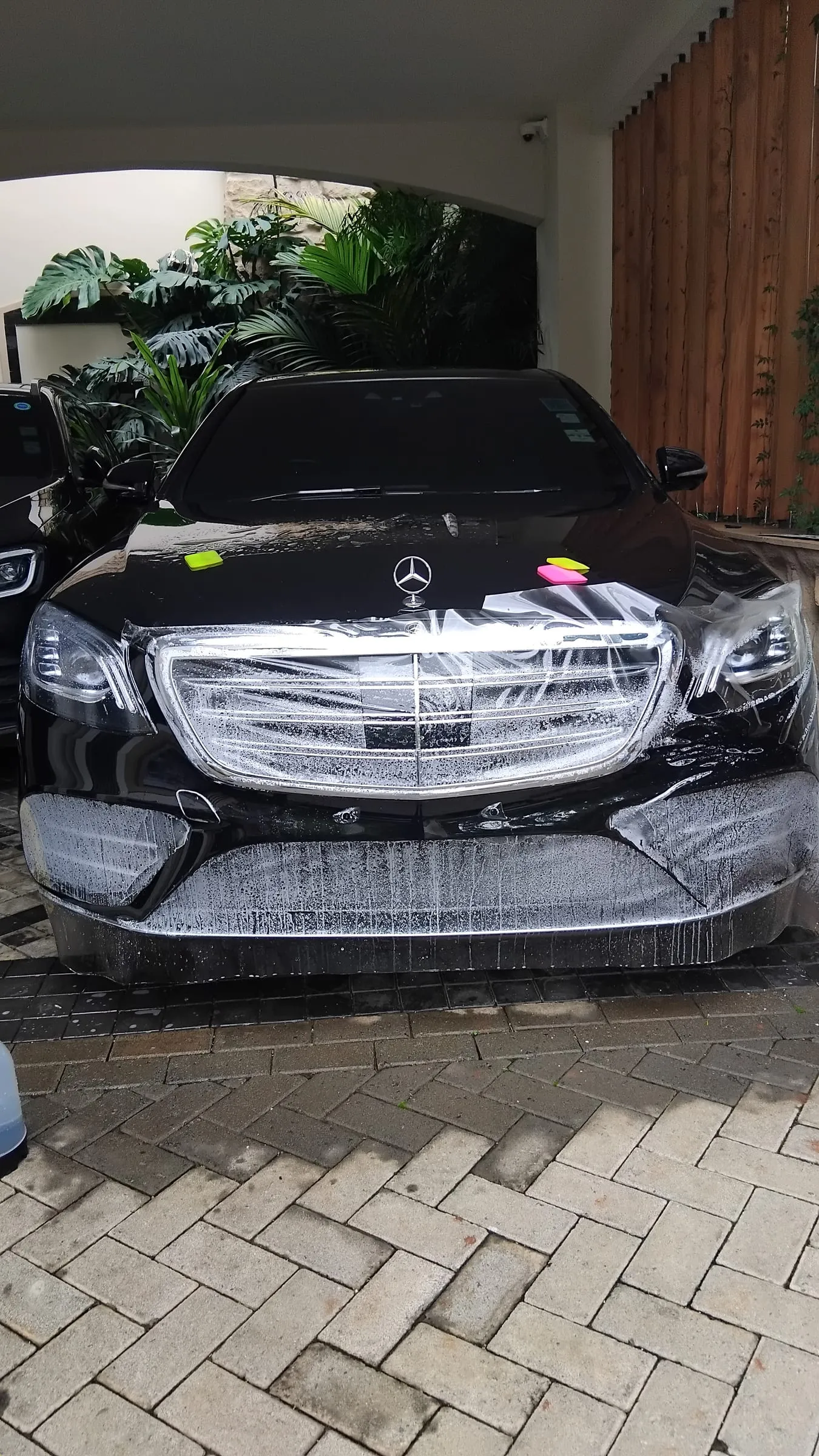 Paint protection film being wet-applied to the front bumper and grille of a black Mercedes-Benz S-Class